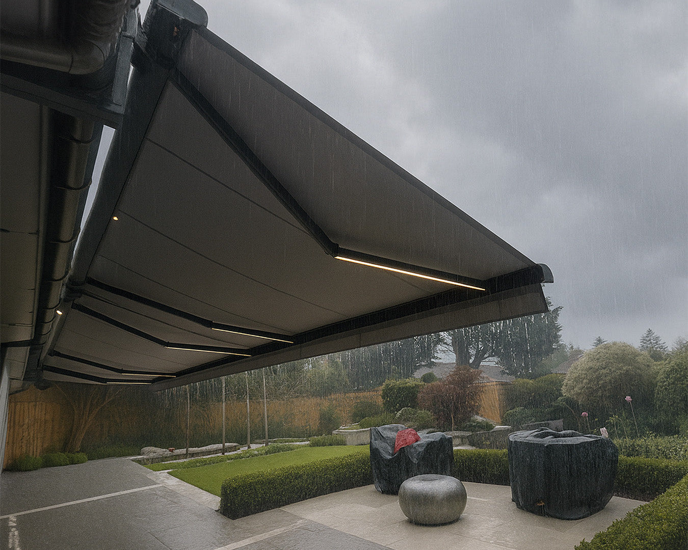 Retractable patio awning sheltering outdoor area from rain in a landscaped garden