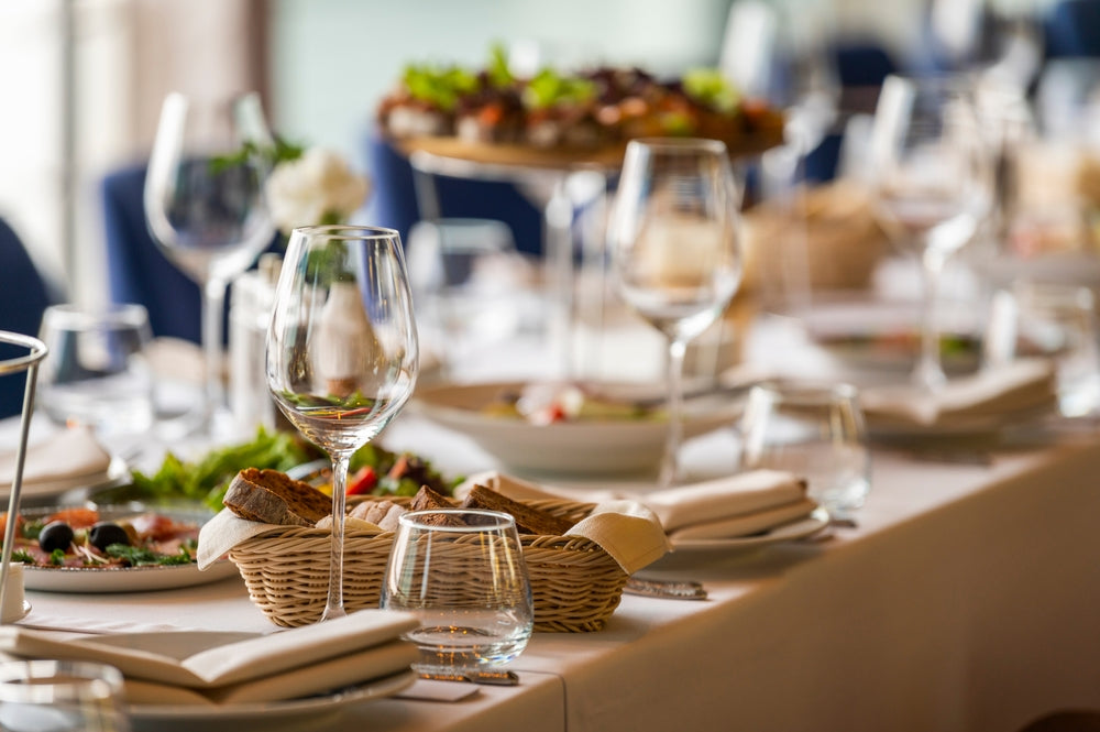 Elegant outdoor dining setup with glassware, wicker bread basket, and decorative plates
