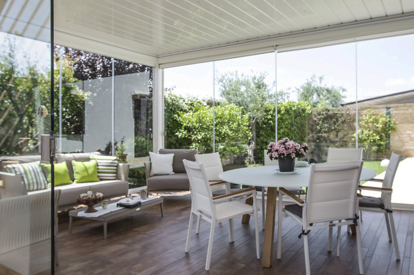 Modern luxury pergola with glass walls, outdoor seating, dining table, and garden view