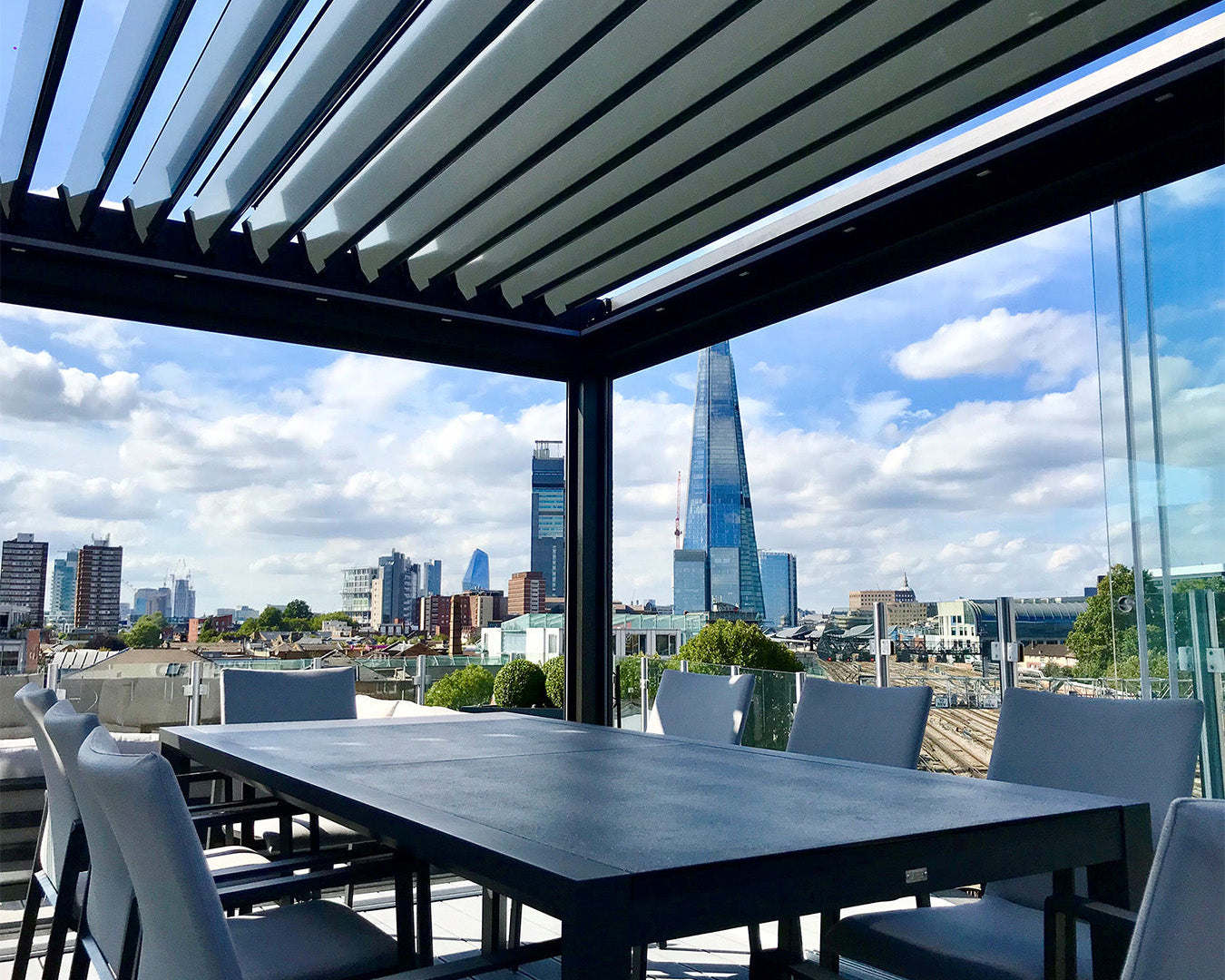 Modern luxury pergola with louvered roof and outdoor dining set overlooking city skyline