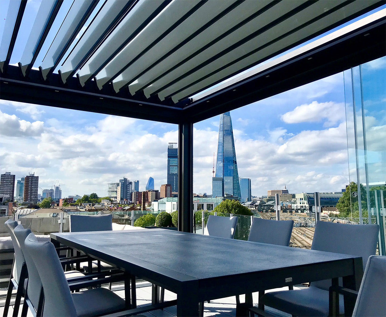 Modern luxury pergola with louvered roof and outdoor dining set overlooking city skyline