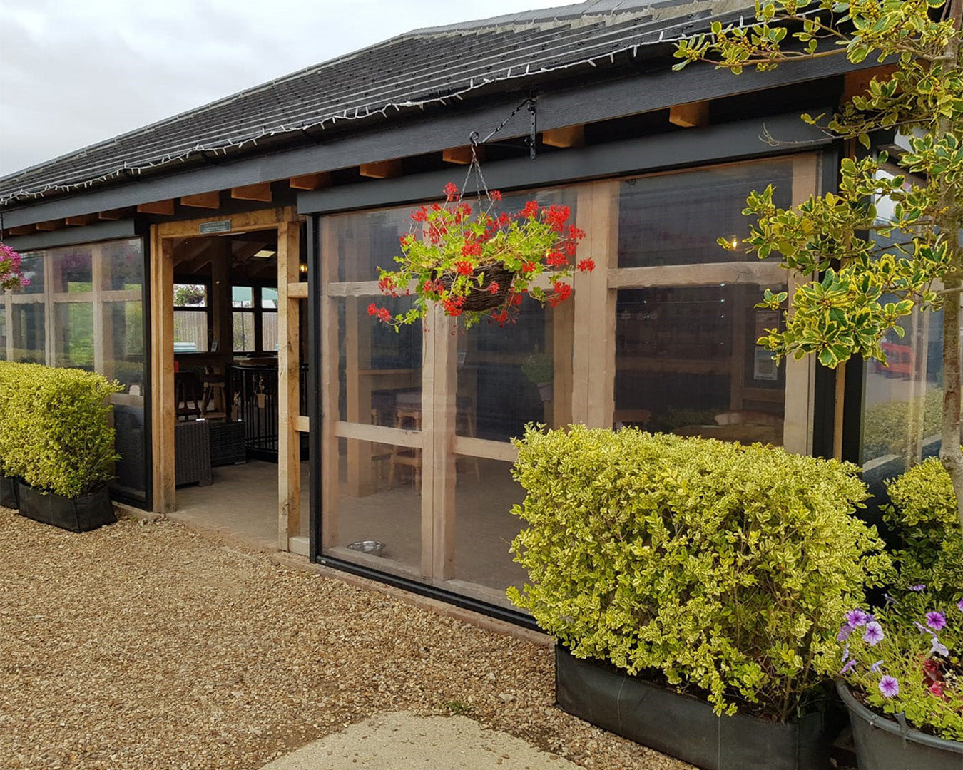 Luxury outdoor covered structure with transparent panels, wooden beams, and modern garden landscaping