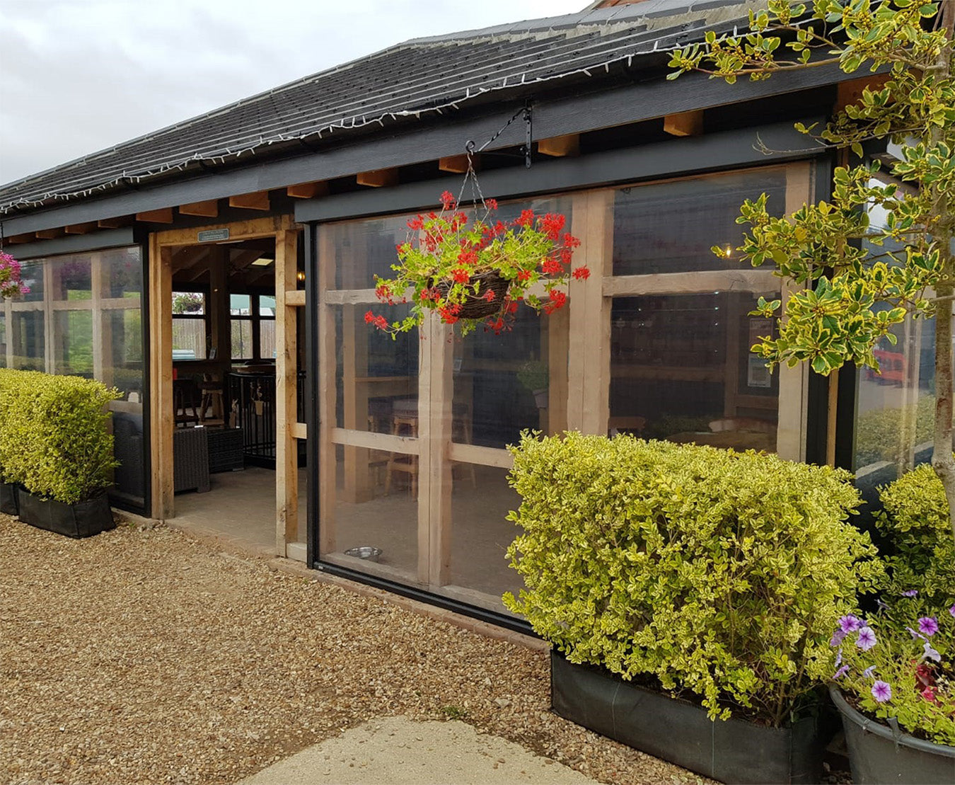 Luxury outdoor covered structure with transparent panels, wooden beams, and modern garden landscaping