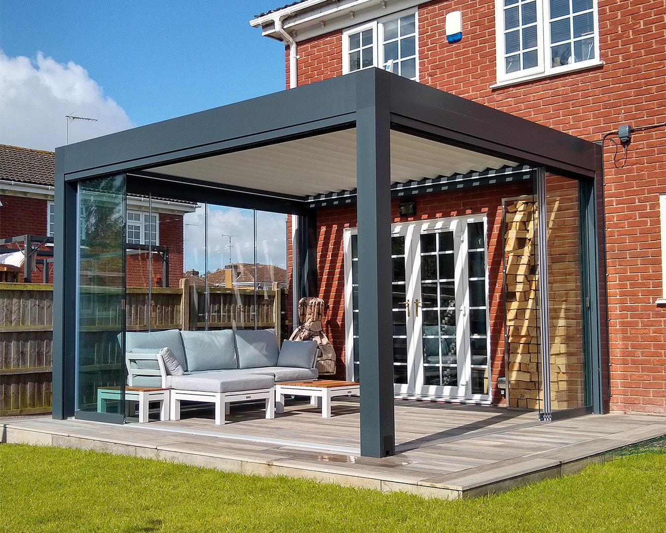 Luxury aluminum pergola with louvered roof and glass walls on a patio by a brick house
