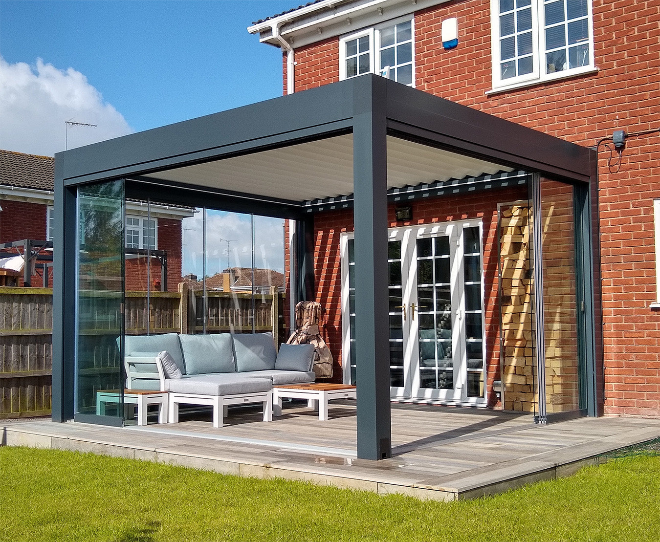 Luxury aluminum pergola with louvered roof and glass walls on a patio by a brick house